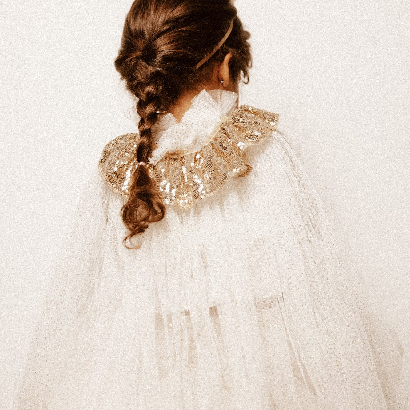 Menina de 4 anos com disfarce de rainha, com uma coroa com glitter, uma varinha mágica com glitter e uma capa com glitter. Disfarces para crianças entre os 3-6 anos.