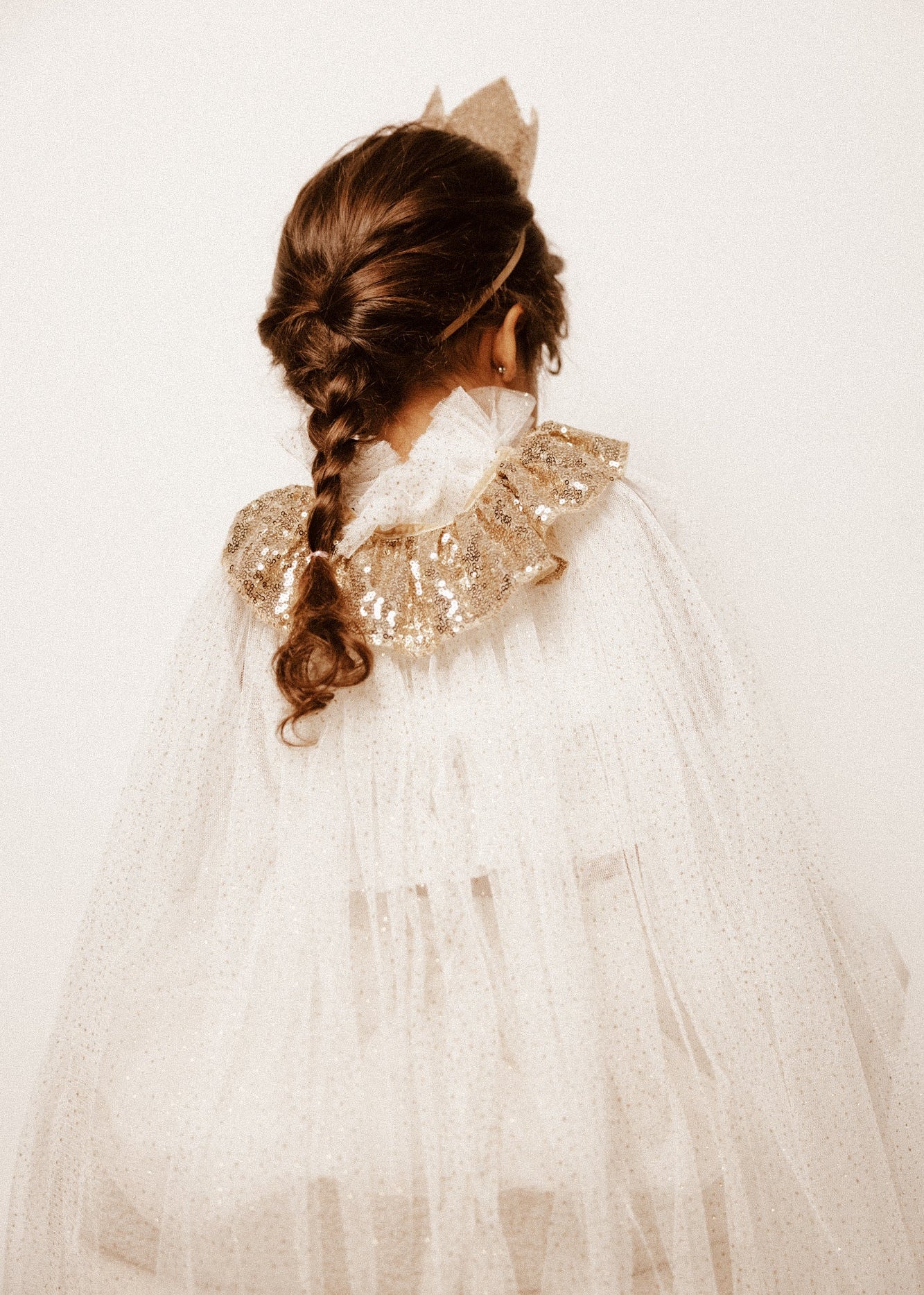 Menina de 4 anos com disfarce de rainha, com uma coroa com glitter, uma varinha mágica com glitter e uma capa com glitter. Disfarces para crianças entre os 3-6 anos.