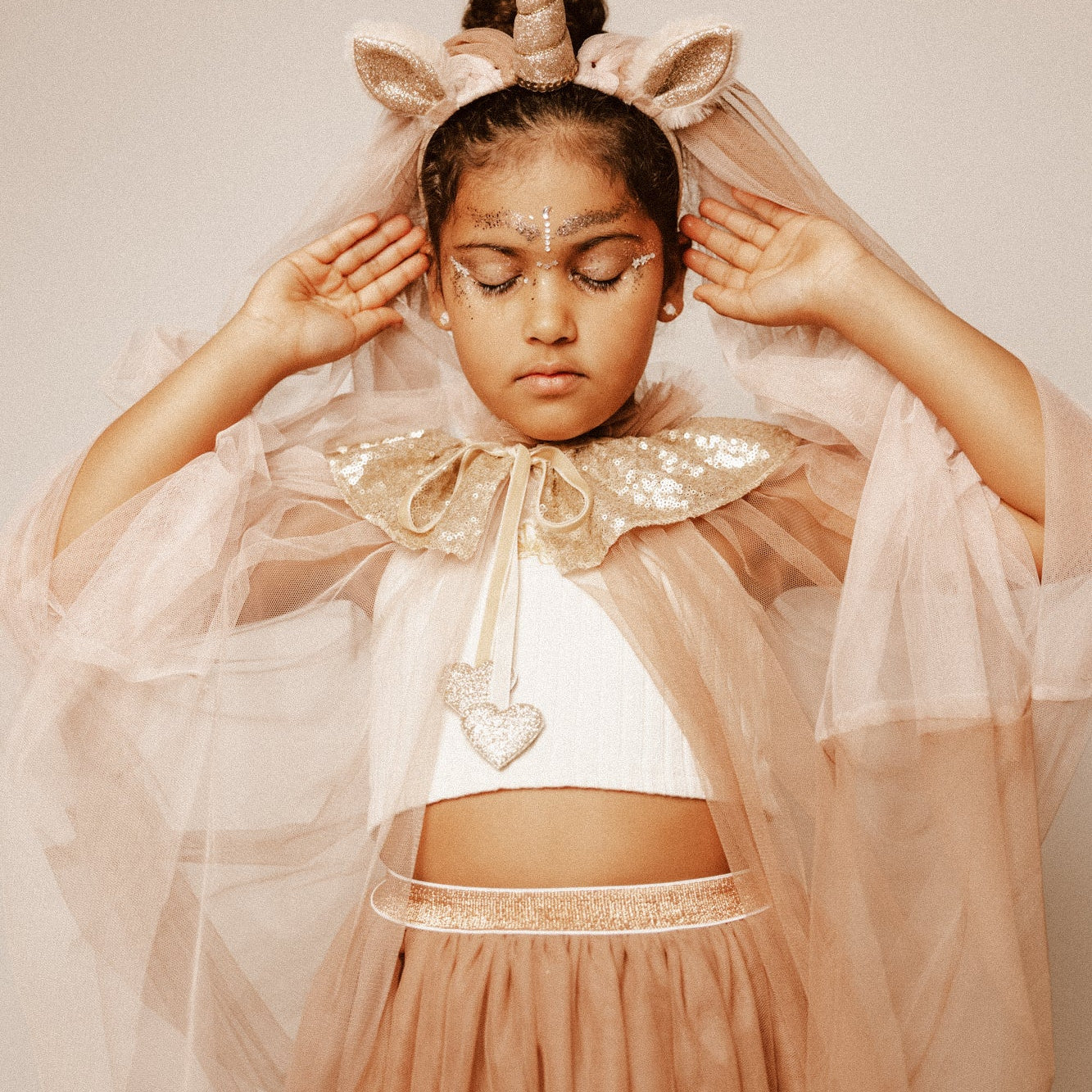 Criança de 7 anos vestida com um disfarce cor-de-rosa de unicórnio , com uma varinha mágica em forma de coração.