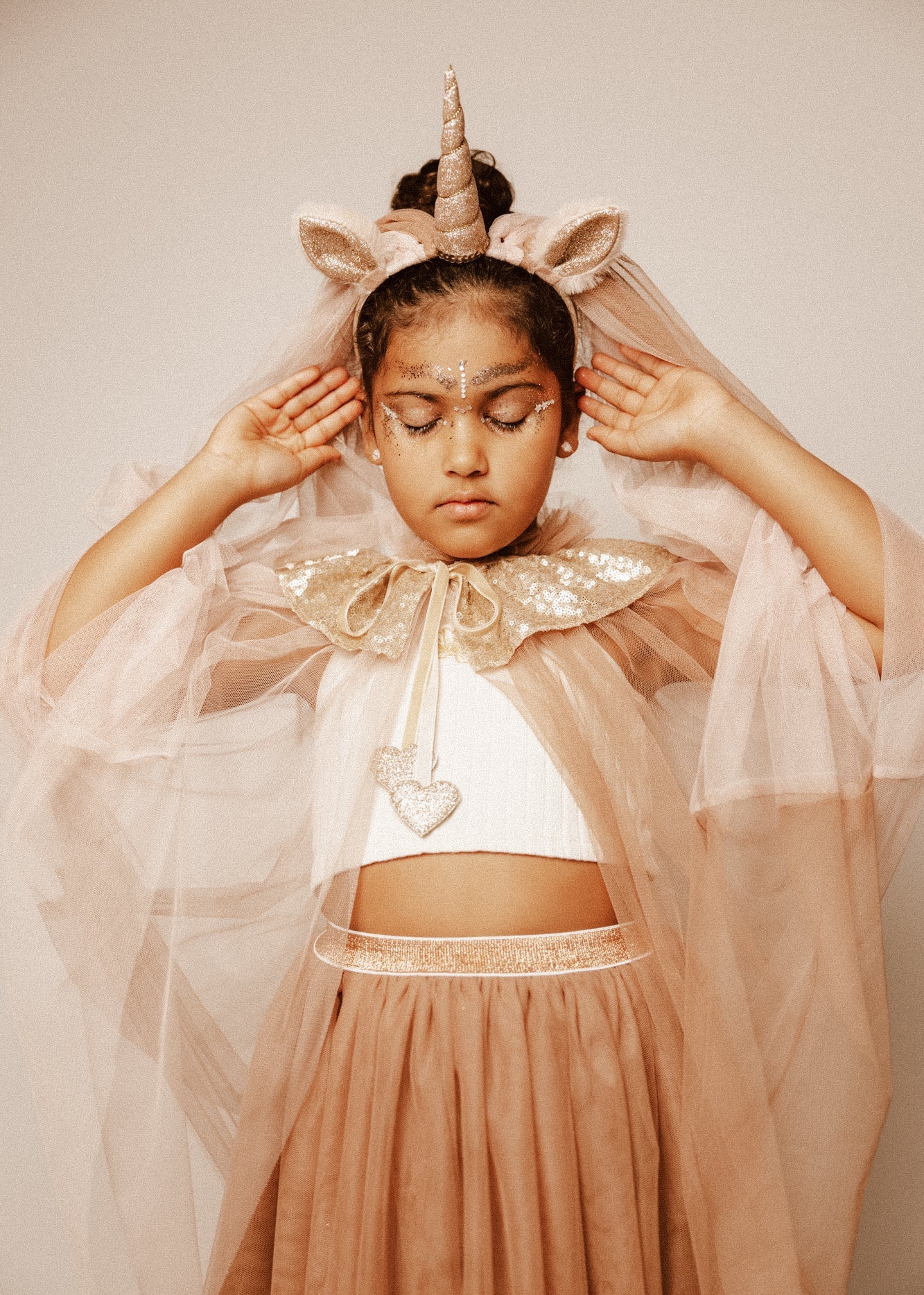 Criança de 7 anos vestida com um disfarce cor-de-rosa de unicórnio , com uma varinha mágica em forma de coração.