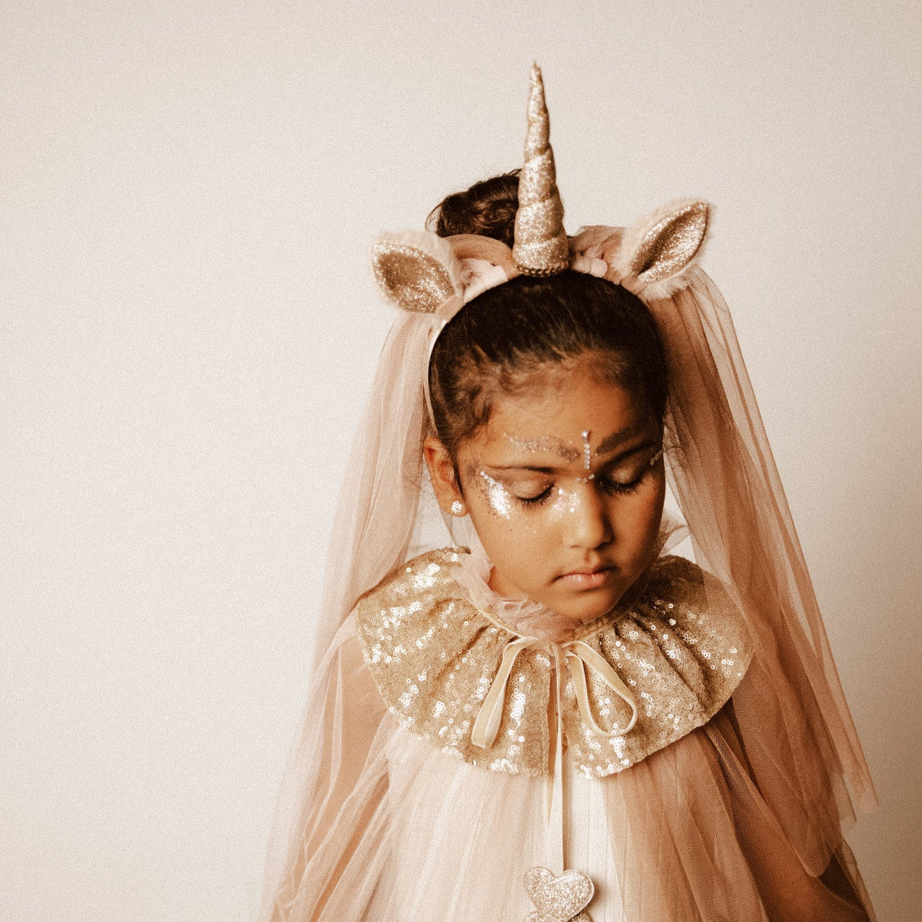 Criança de 7 anos vestida com um disfarce cor-de-rosa de unicórnio , com uma varinha mágica em forma de coração.