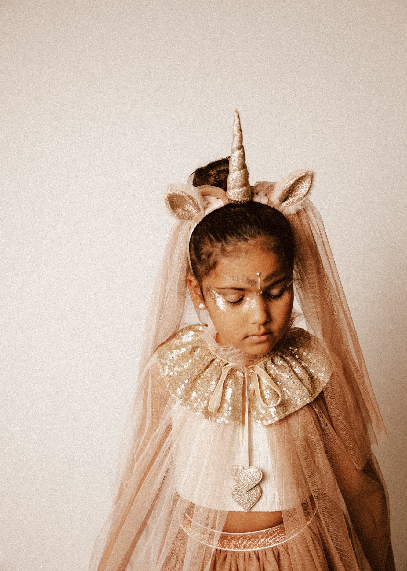 Criança de 7 anos vestida com um disfarce cor-de-rosa de unicórnio , com uma varinha mágica em forma de coração.