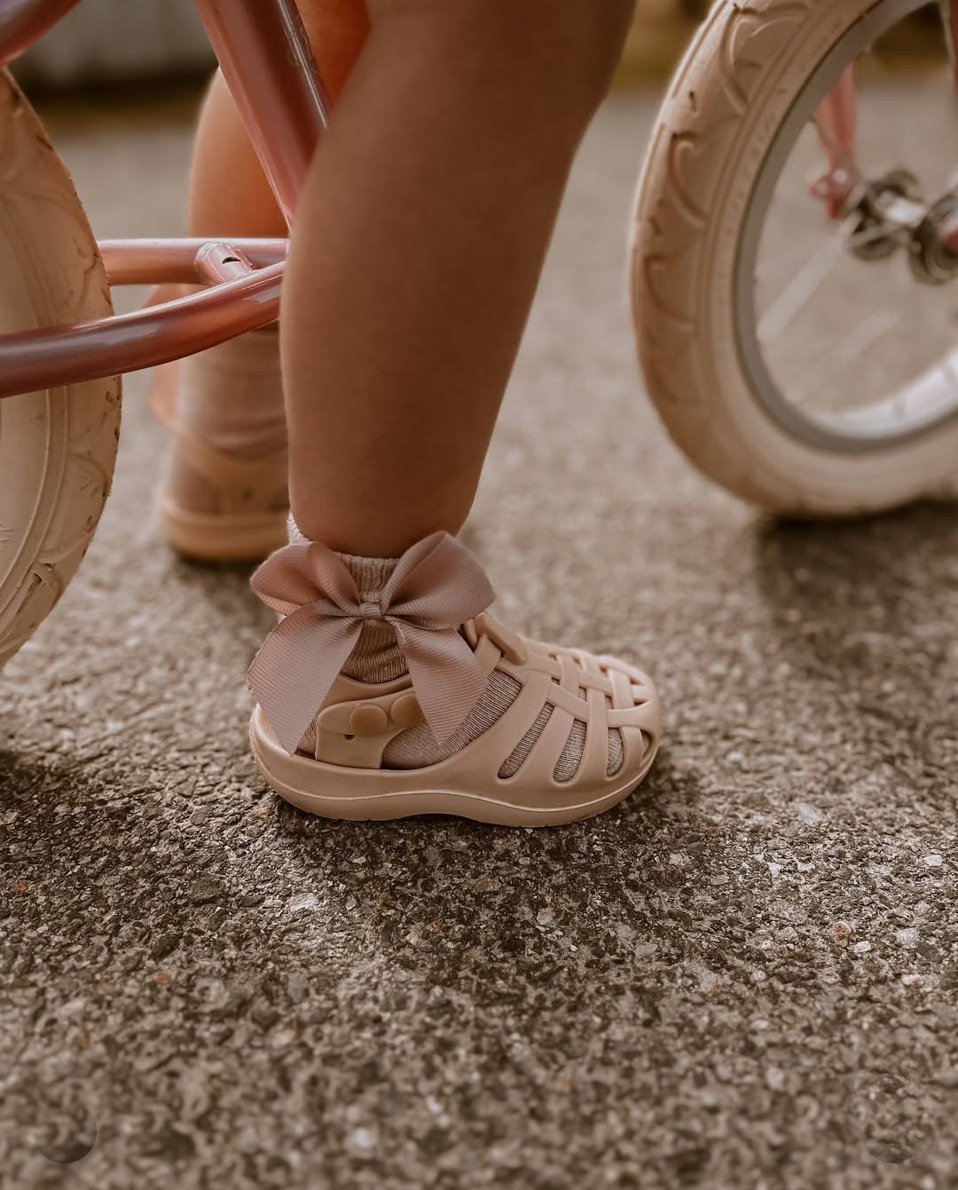 Plano aproximado dos pés de uma criança a utillizar sandálias em cor de rosa